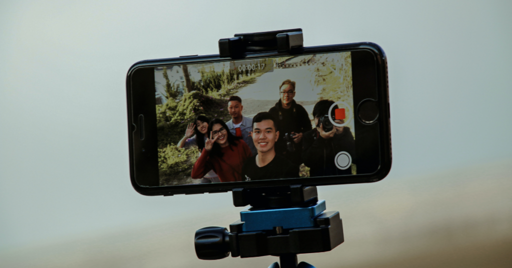 A group of people recording themselves using the front-facing camera on a smartphone mounted to a stabilizer 