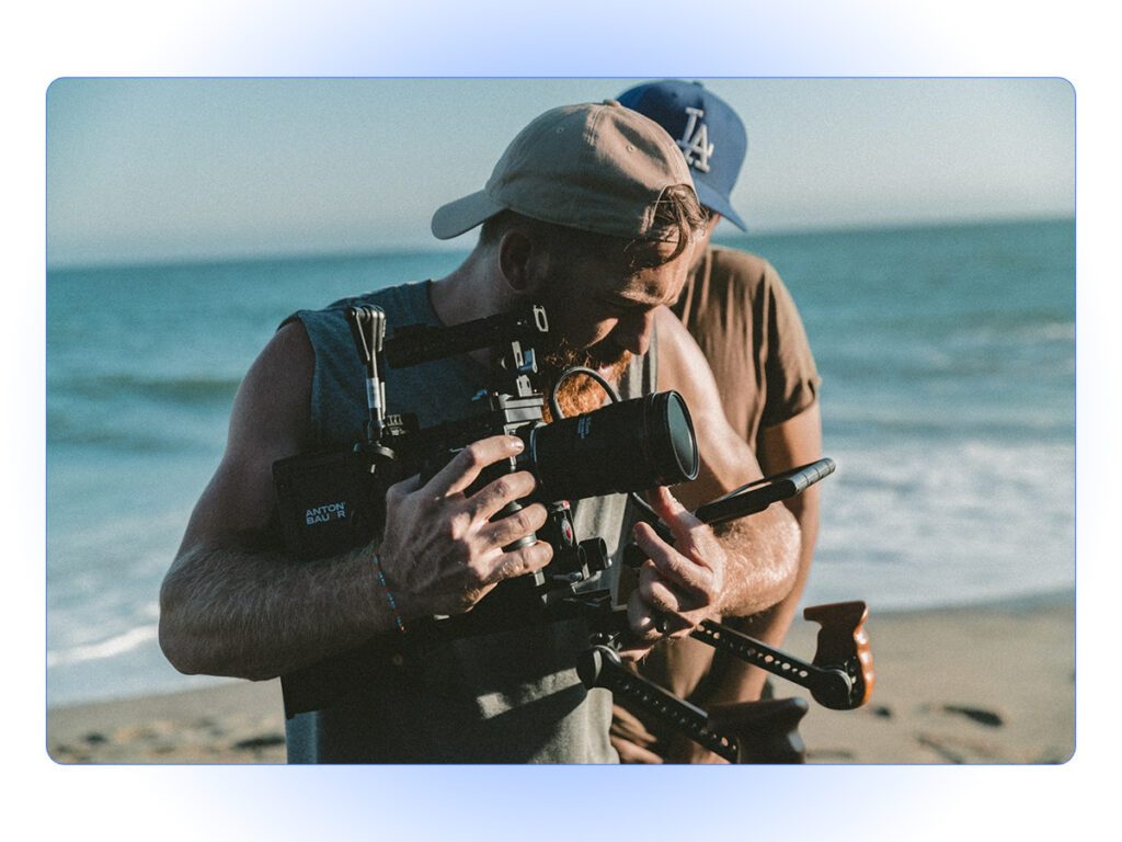 Two men recording a video on the beach - video marketing is another of our summer marketing ideas.